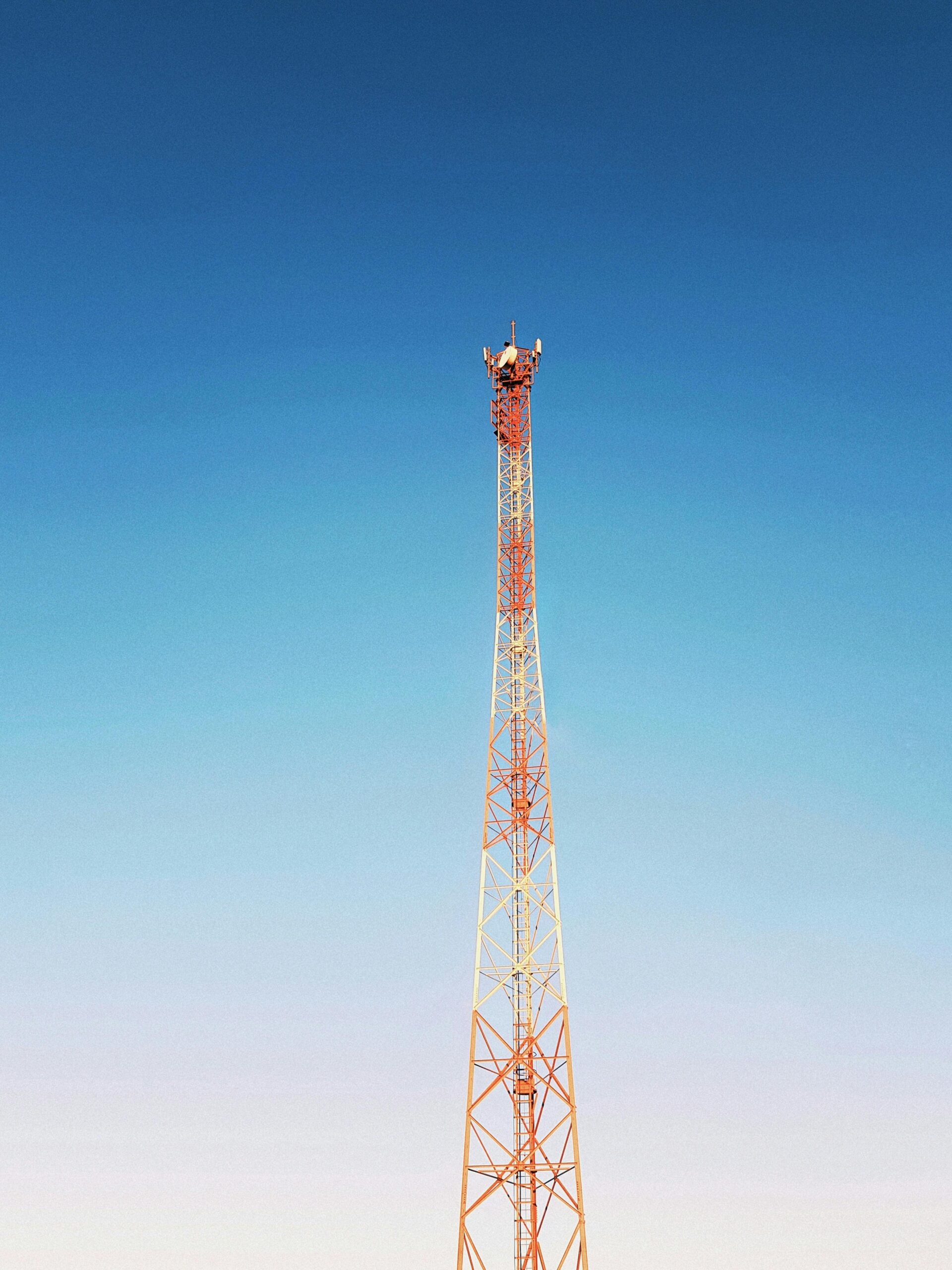 A lone communication tower stretching towards a clear blue sky, symbolizing modern connectivity.